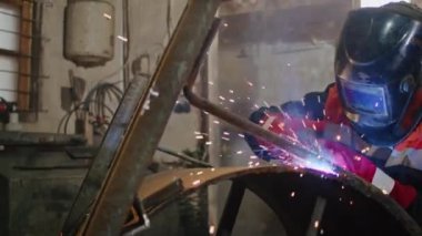 Bir kaynakçı olarak teknolojinin ve işçiliğin gücünü bir üretim tesisinde metali kaynaştıran kıvılcımlar üretmek için elektrotlar kullanarak hassas bir şekilde çalışmasını deneyimleyin..