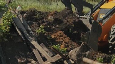 İnşaat ve teknoloji sinerjisini keşfederek diğer ekipmanlarla çevrili büyük bir kazıcı olarak güneşli bir gökyüzünün arkaplanına karşı gelişimin sembolüne dönüştürür..
