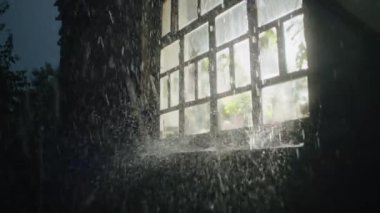 Karanlık bir gecede yağmur damlaları pencerenin cam yüzeyinden aşağı taşarken, şehir bulanık ışıklar ve parıldayan yansımalarla canlanıyor, soyut bir kentsel tuval boyuyor..