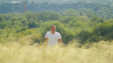 Güneş ışınları tarlayı okşarken, bir adam kollarını ardına kadar açar, doğanın güzelliğinde mutluluk ve özgürlüğü bulur..