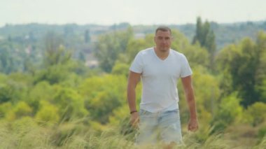 Güneş tarlanın üzerinde batarken, bir adam açık kollar doğanın güzelliğinde bulunan özgürlüğü ve mutluluğu simgeler..