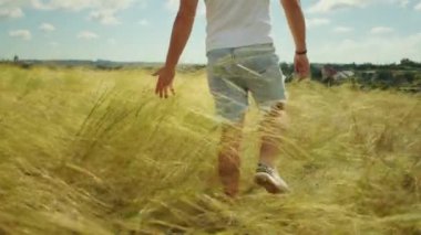 Kolları geniş ve kalbi açık bir adam, bir tarlada gün batımını seyrediyor, doğanın ve kırsal kesimin neşesini yakalıyor..