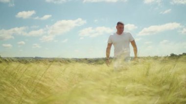 Güneş ufkun altına batarken, bir adam bir tarlada duruyor, kollarını açmış, açık havanın özgürlüğünü kucaklıyor..