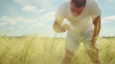 Tarladaki bir adam kollarını batan güneşe doğru kaldırır, doğada bulunan özgürlük ve mutluluk hissini somutlaştırır..
