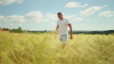 Kolları açık, gün batımında eğlenen bir adam kırsal kesimin neşe ve sükunetini kutluyor..