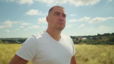 Gün batımında gökyüzünü boyayan bir adam tarlada duruyor, kolları açık kırsal kesimin mutluluğunu ve huzurunu kucaklamak için..