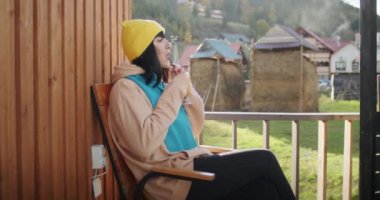 Sarı bereli bir kadın kırsal alanda içki içiyor. Boş zaman ve rahatlama konsepti. Yaşam tarzı blogu, seyahat rehberi ve açık hava yaşam dergisi için tasarım. Doğal manzaralı geniş açı.