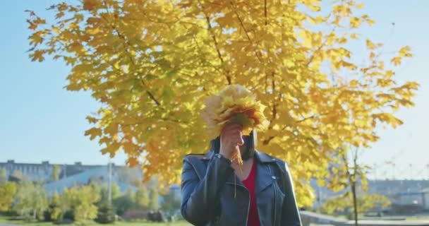 Frau Mit Gelber Mütze Die Einen Strauß Herbstblätter Der Hand — Stockvideo