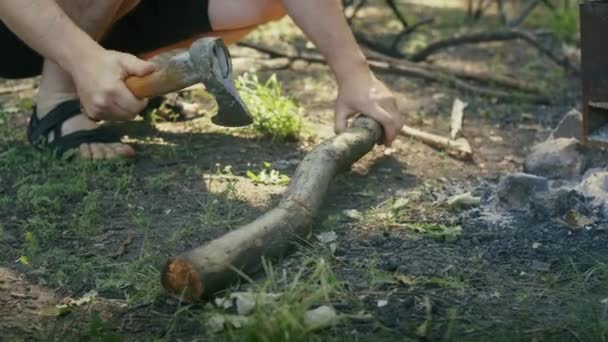 キャンプファイヤーサイトの近くで斧で薪を切る人 アウトドアサバイバルとキャンプコンセプト 指導材料のための設計 屋外装置の広告 — ストック動画