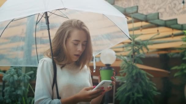 Frau Mit Regenschirm Mit Smartphone Und Kaffeetasse Der Hand Regentag — Stockvideo