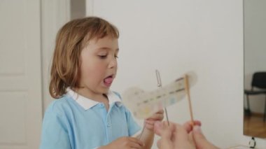 Terapi ofisinde mutlu yankılar: çocuk, beyazlar içinde konuşma patologu, oyun yoluyla dil öğrenme. Birlikte büyüyorlar..