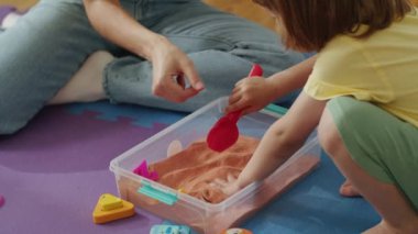 Yetişkin ve çocuk kinetik kumla duyusal oyun oynuyorlar. Gelişimsel oyun ve duyusal bütünleşme kavramı. Çocuk gelişimi kaynakları, mesleki terapi faaliyetleri ve ebeveynlik için tasarım