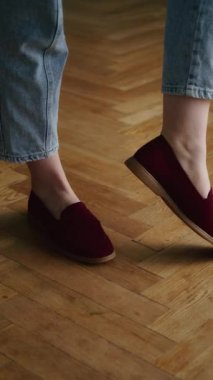 Herringbone parke zemininde sarılmış mavi kotlu bordo ayakkabı giyen bir adam. Günlük ayakkabı stili ve tasarım ve reklam için rahat moda konsepti.