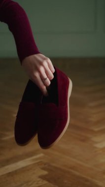 Ahşap zeminde bordo ayakkabılarla el ele tutuşmak. Tasarım ve kopya için alanı olan ayakkabı modası için ürün sunumu.