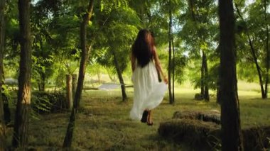 Ormanda yürüyen beyaz elbiseli bir kadın. Tasarım ve baskı için sükunet ve doğa kavramı.