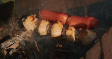 Kamp ateşinde ızgara yapan sosis ve mantarlar. Açık hava yemekleri ve barbekü konsepti. Tasarım ve baskı için kamp yaşam tarzı ve eğlence aktivitesi. Duman ve doğal ışık ile yakın çekim.