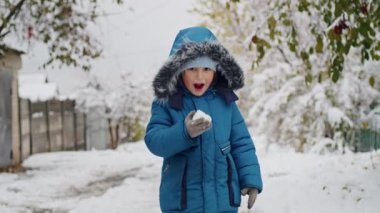 Mavi kışlık ceketli çocuk kar yiyor. Tasarım ve baskı için kış ve çocukluk kavramı.