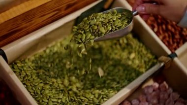 Organik bakkaldaki çöp kutusundan balkabağı tohumu topluyorum. Sağlıklı ve doğal gıda seçilimine yakın çekim. Çevre dostu ve sıfır atık alışveriş konsepti.