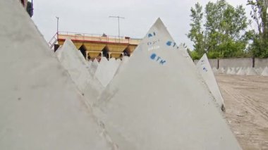 Endüstriyel bir inşaat sahasında depolanmış beton piramit şekilli bloklar. Güçlendirilmiş beton yapıların imalatı ve depolanması.