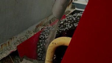 Parçalanmış taş ve kum, inşaat alanındaki bir boşaltma borusundan endüstriyel taşıma bandına yükleniyor. Ağır makinelerin faaliyet halindeki yakın görüntüsü.