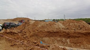 Büyük çakıl yığınları ve kümelenmiş malzemelerle dolu sanayi deposu. İnşaat alanında malzeme depolamak için kullanılan beton kutular.