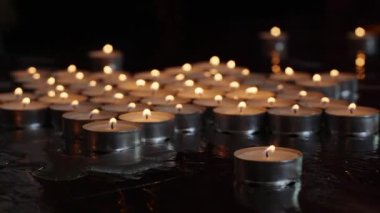 Yansıtıcı yüzeyde koyu renkte yanan gece lambası mumlarının yakın çekimi. Mum ışığı ve hatıra konsepti tasarım ve baskı için.