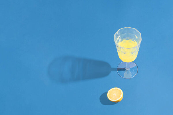 Minimal contrast idea with yellow lemon drink on blue background. Minimal colourful party concept.