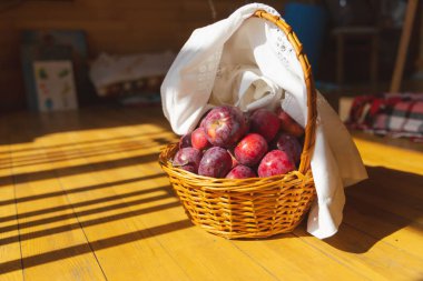 Tahta zeminde kırmızı elmalarla örülmüş sepet.