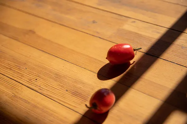 stock image Red Tomatoes on Wooden Floor Under Sunlight