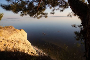 Etrafı Lush Trees, Grass ve Rocky Cliffs ile çevrili bir tepeden Serene Waterbody 'nin Hava Görüntüsü - Güzel Doğa Manzarası