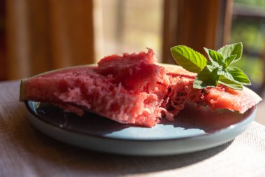 Kırmızı karpuz eti ve dilimler mavi tabakta yeşil nane şekeri taze ve renkli yaz ziyafeti ile