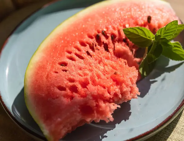 stock image Red Watermelon Flesh and Slices on a Blue Plate with a Green Mint Sprig  Fresh and Colorful Summer Treat