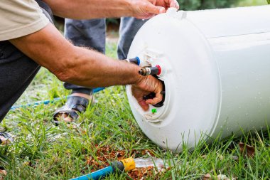 Su ısıtıcısını suyla temizleyen, su ısıtıcısını tamir eden adam.