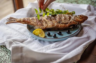 Limonlu ve otlu ızgara balık, servis için elle süslenmiş.