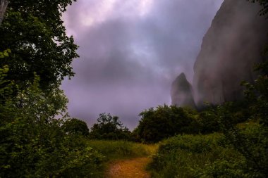 Misty Rock in Meteora, Greece, with Trees at the Base  Dramatic Mountain Landscape in Cloudy Weather, Nature and Travel clipart