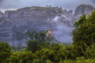 Yunanistan 'ın Meteora kentindeki Puslu Kaya' da, Bulutlu Hava, Doğa ve Seyahatte Üs Dramatik Dağ Manzarasında Ağaçlar