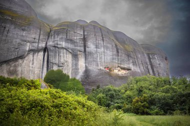 Misty Rock in Meteora, Greece, with Trees at the Base  Dramatic Mountain Landscape in Cloudy Weather, Nature and Travel clipart