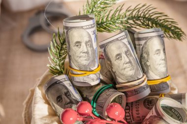 Festive Financial Gift Concept with Rolled US Dollar Bills and Holiday Decorations for New Year Prosperity clipart