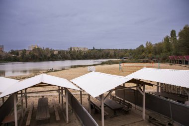 Kumsalda, ahşap masalı ve Riverside manzaralı bir piknik alanı.