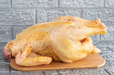 Fresh chicken with golden skin, ready for sale, close-up on a gray background clipart