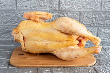 Fresh chicken with golden skin, ready for sale, close-up on a gray background clipart