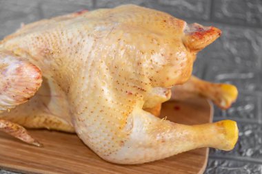 Altın tenli taze tavuk, satılmaya hazır, yakın plan gri arka plan.