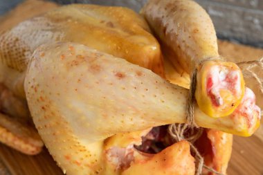 Altın tenli taze çiğ tavuk, pişirmeye hazır, gri arka planda yakın plan.