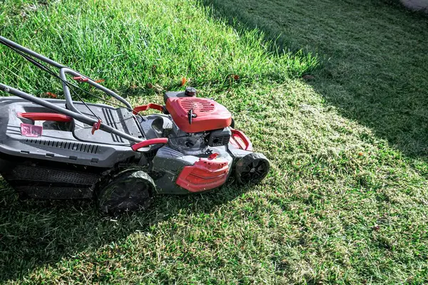 Çimlerin üzerindeki çim biçme makinesinin yakın plan çekimi.