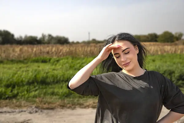 Doğada güneşli bir günün tadını çıkaran genç bir kadın, huzur içinde gözleri kapalı.