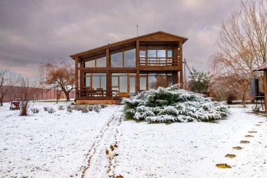 Kışın ahşap kır evi, güneşli ve sıcacık manzaralı.