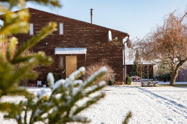 Kışın ahşap kır evi, güneşli ve sıcacık manzaralı.