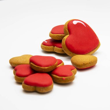 Kalp şeklinde zencefilli kurabiye ve beyaz arka planda kırmızı krema.