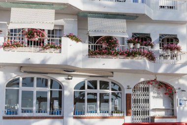 Çiçekli Balkon ve Güneş Gölgeleriyle Beyaz Akdeniz Binası Cephesi