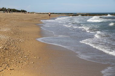 Okyanus dalgaları kumlu sahile çarpıyor. Uzakta dalgalar var..